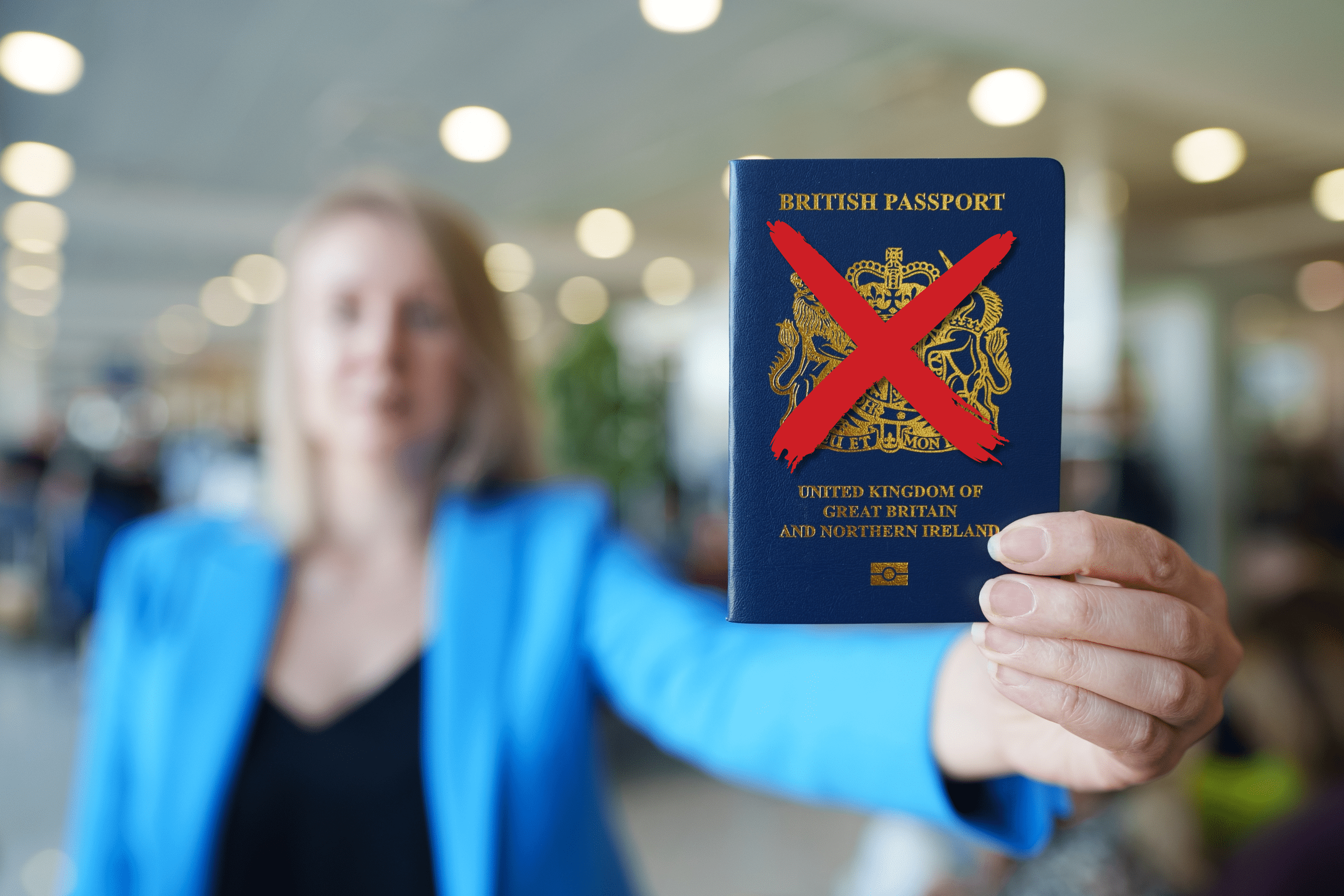 Woman holding a UK passport with a red cross on it representing deprivation of citizenship